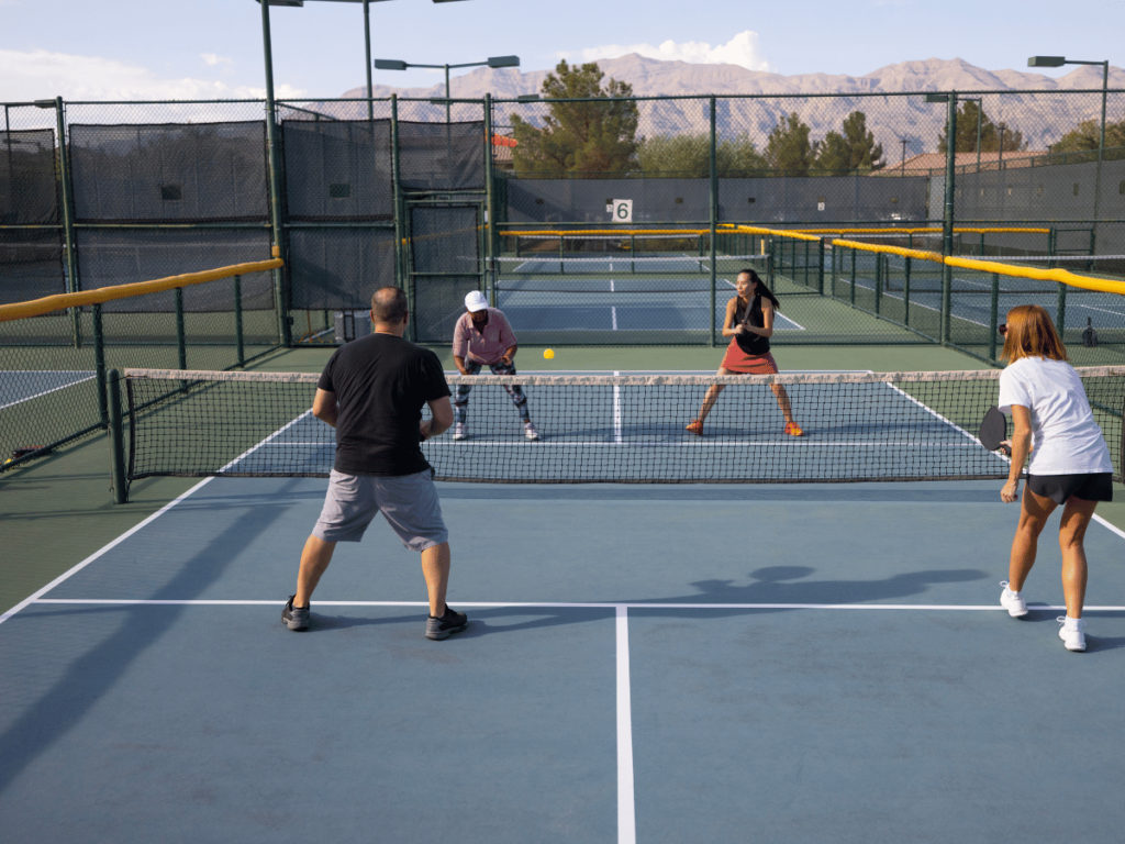 four people playing pickleball on a blue court