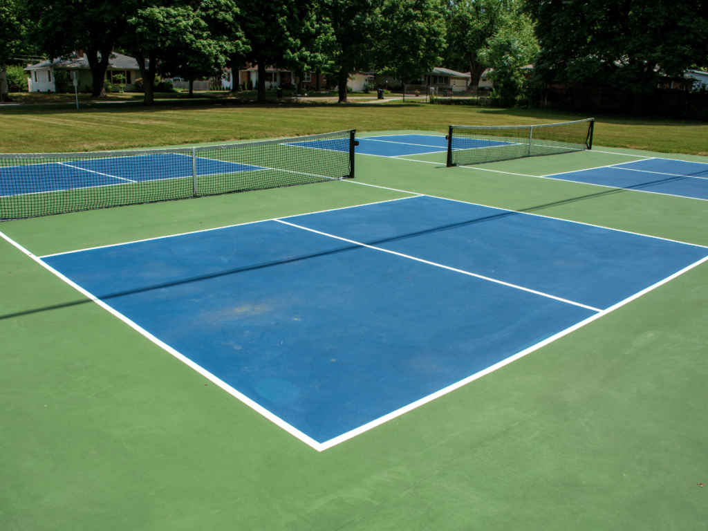 Blue pickleball court with green surround and green no volley zone