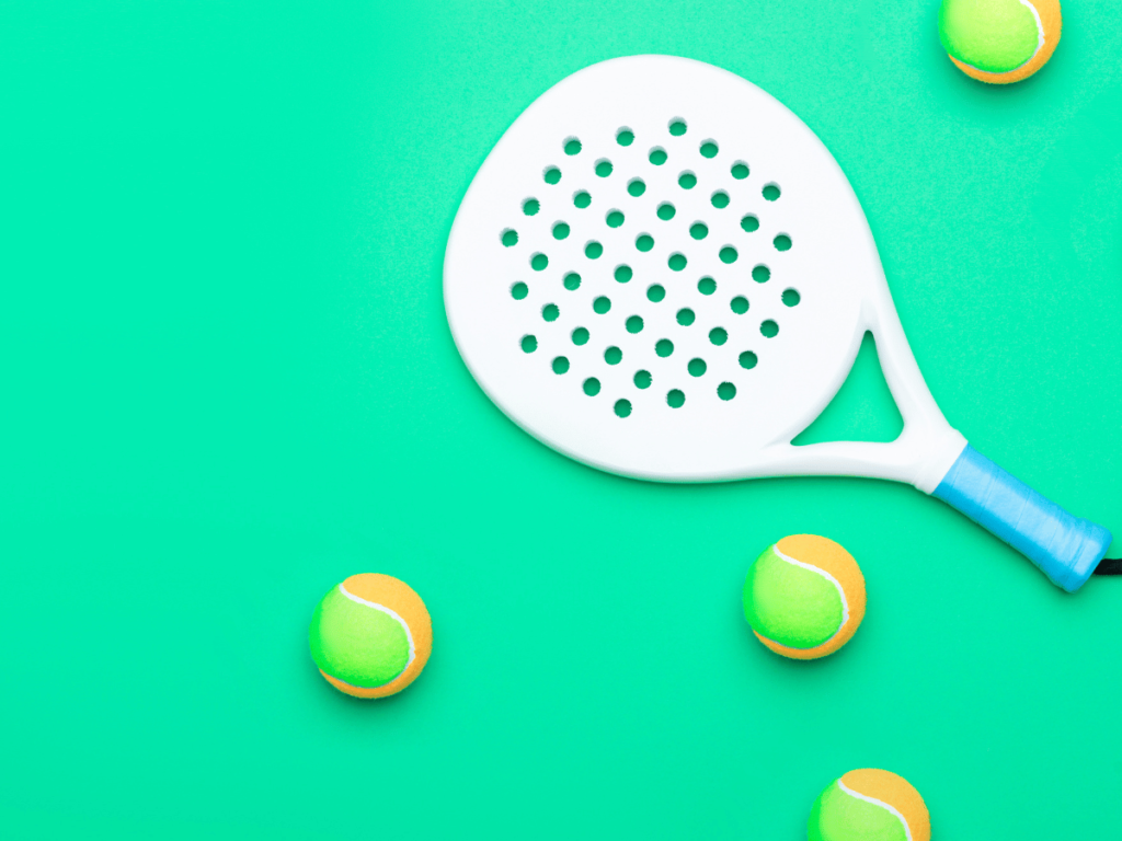 White padel racket with green and orange balls on green background